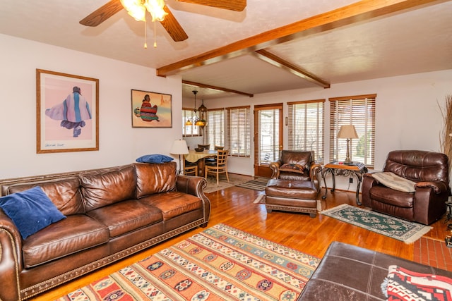 living room with beamed ceiling, ceiling fan with notable chandelier, and wood finished floors