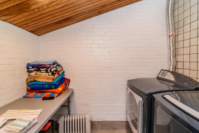 washroom with wooden ceiling, radiator heating unit, brick wall, washer and dryer, and laundry area