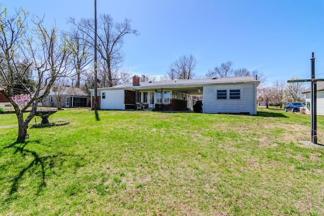 back of property featuring a yard, metal roof, and a chimney