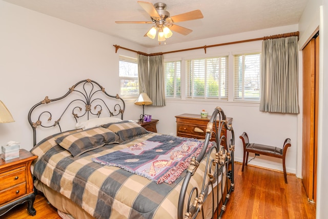 bedroom with a closet, wood finished floors, baseboards, and ceiling fan