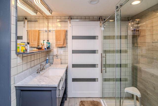 full bathroom featuring a shower stall, tile walls, vanity, and decorative backsplash