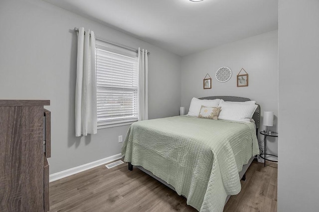 bedroom featuring baseboards, visible vents, and wood finished floors