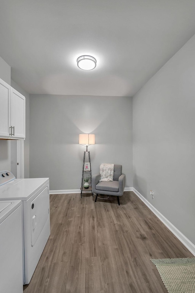 laundry room with cabinet space, washing machine and dryer, baseboards, and dark wood-type flooring