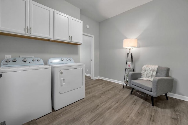 laundry room featuring baseboards, cabinet space, washing machine and dryer, and light wood-style flooring