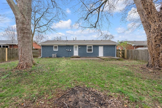 rear view of property featuring central AC, brick siding, a fenced backyard, and a lawn
