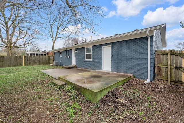 back of property with fence, a patio, central AC unit, brick siding, and a yard