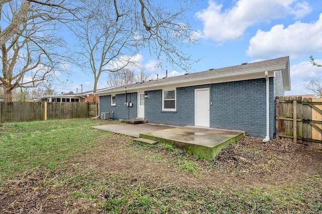 back of property with central AC unit, a patio, a fenced backyard, brick siding, and a lawn