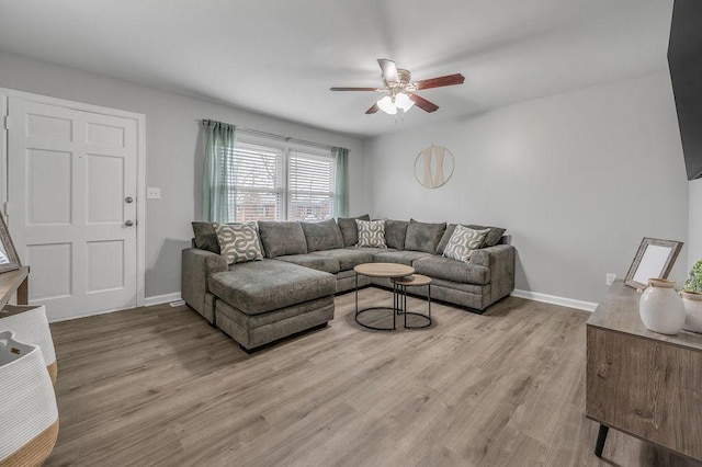 living area featuring baseboards, ceiling fan, and light wood-style floors
