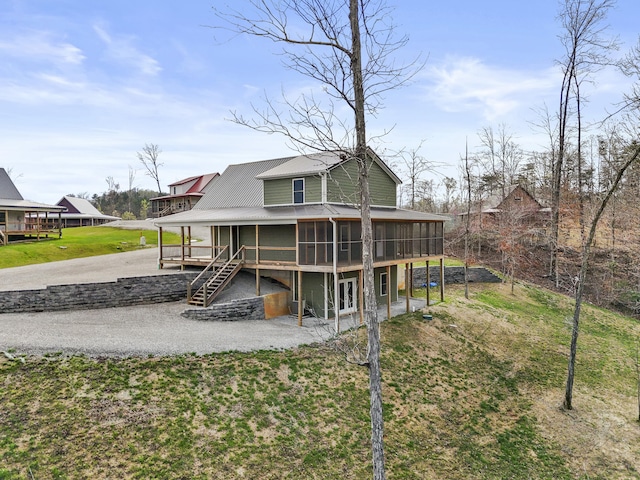 back of house featuring a lawn, a sunroom, and stairway