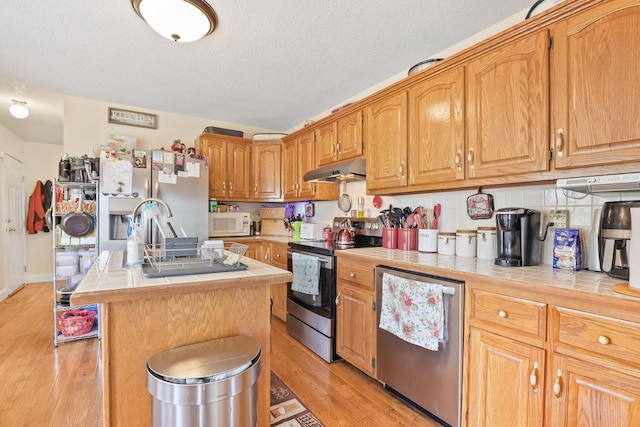 35 Fox Trail Rd, Manchester, KY 40962 - kitchen featuring a kitchen island, tile counters, stainless steel appliances, and under cabinet range hood