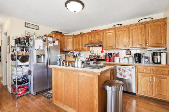 35 Fox Trail Rd, Manchester, KY 40962 - kitchen with light countertops, a kitchen island with sink, appliances with stainless steel finishes, under cabinet range hood, and light wood-style floors