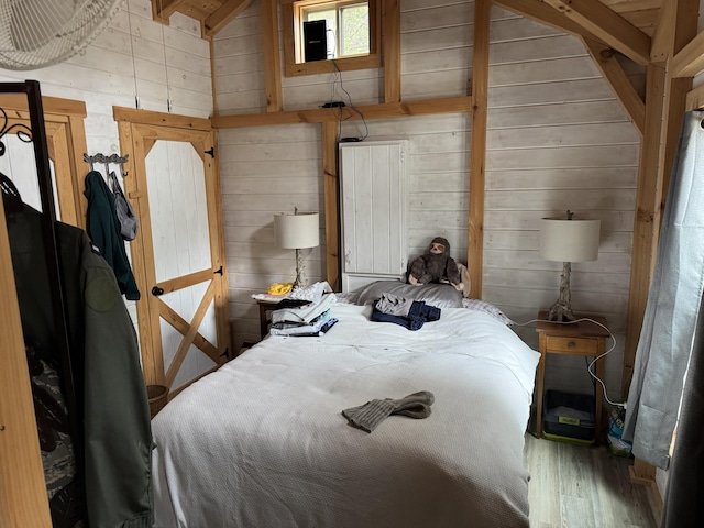 unfurnished bedroom with high vaulted ceiling, wooden walls, wood finished floors, and beam ceiling