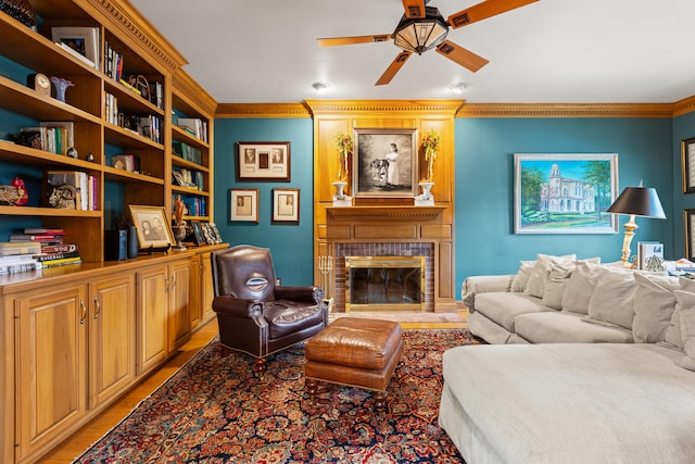 living area featuring ceiling fan, light wood-style floors, a fireplace, and ornamental molding