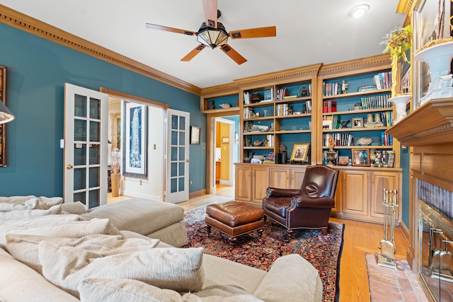 living area with ceiling fan, crown molding, baseboards, and light wood finished floors
