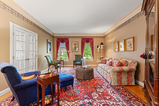 living room featuring wood finished floors, baseboards, crown molding, and wallpapered walls