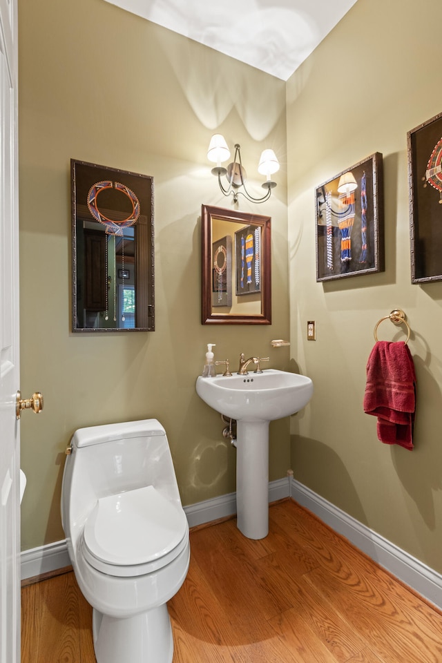bathroom with wood finished floors, baseboards, and toilet