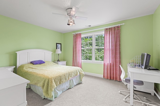 bedroom featuring light carpet, baseboards, ceiling fan, and a desk