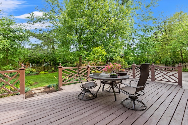 deck with outdoor dining area and view of wooded area