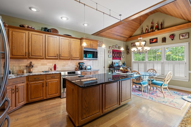 kitchen featuring appliances with stainless steel finishes, a kitchen island, brown cabinetry, dark stone counters, and vaulted ceiling