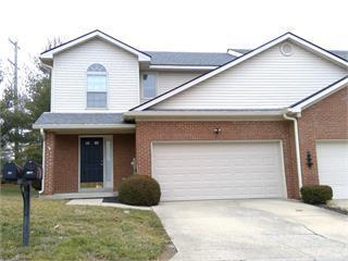 traditional home featuring driveway, a front yard, an attached garage, and brick siding