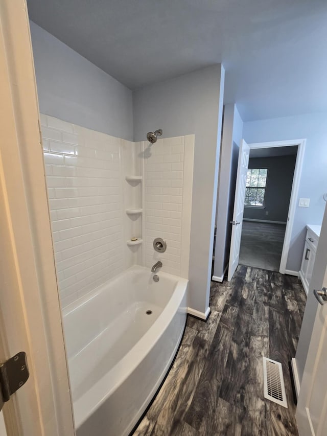bathroom featuring visible vents, baseboards, wood finished floors, vanity, and shower / bathing tub combination