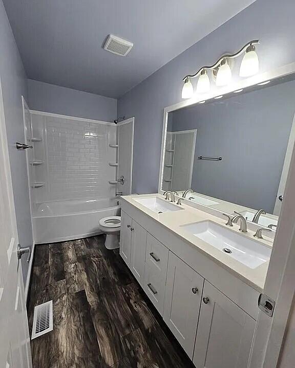 bathroom with wood finished floors, a sink, and visible vents