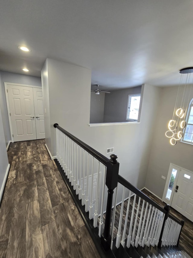 staircase with wood finished floors, ceiling fan with notable chandelier, baseboards, visible vents, and recessed lighting