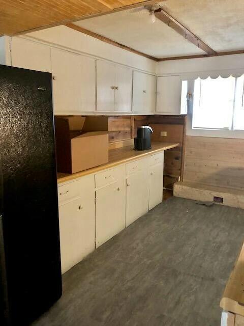 34 Owens Rd S, Clearfield, KY 40313 - kitchen with white cabinets, light countertops, wooden walls, and freestanding refrigerator