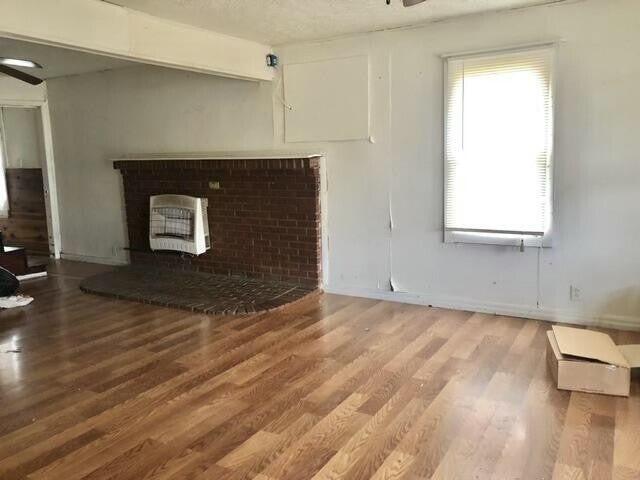 34 Owens Rd S, Clearfield, KY 40313 - unfurnished living room with wood finished floors, ceiling fan, and a brick fireplace