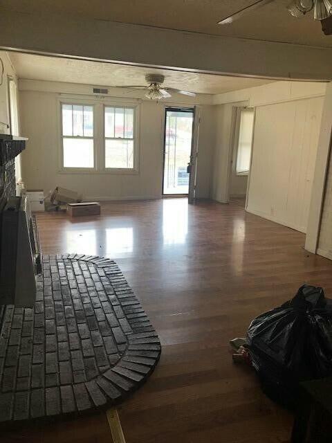 34 Owens Rd S, Clearfield, KY 40313 - unfurnished living room with a ceiling fan, beamed ceiling, a fireplace, and wood finished floors