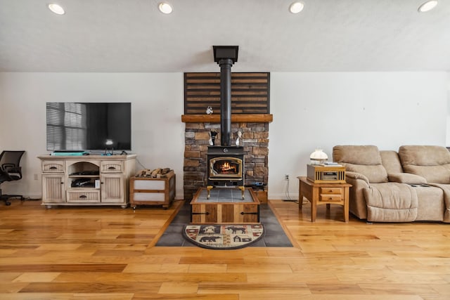 living room with recessed lighting, baseboards, light wood finished floors, and a wood stove
