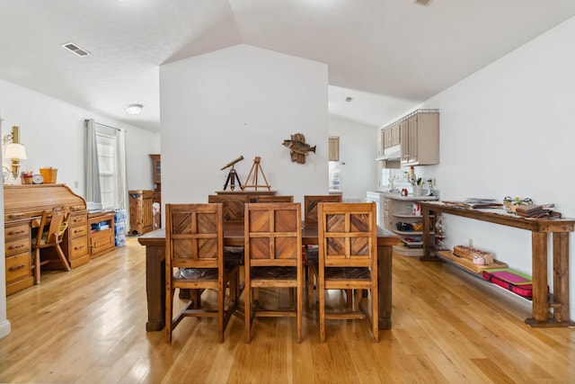 dining space with vaulted ceiling, visible vents, and light wood-style floors