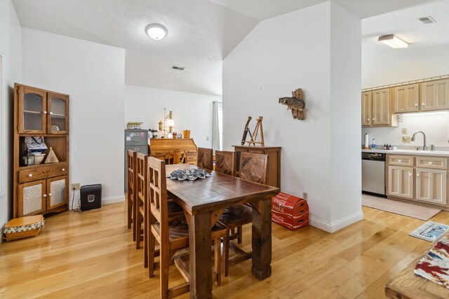 dining space featuring baseboards, lofted ceiling, and light wood-style flooring