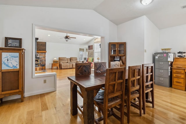 dining area featuring visible vents, light wood-style flooring, baseboards, ceiling fan, and vaulted ceiling
