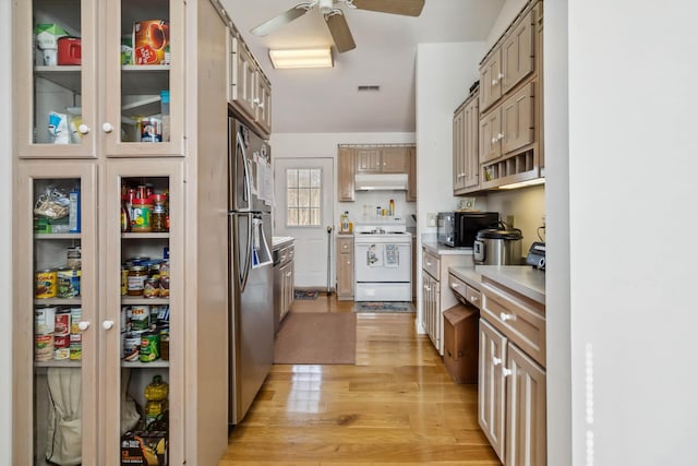 kitchen featuring white electric range oven, light countertops, under cabinet range hood, black microwave, and freestanding refrigerator