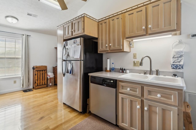 kitchen with light countertops, visible vents, light wood finished floors, stainless steel appliances, and a sink