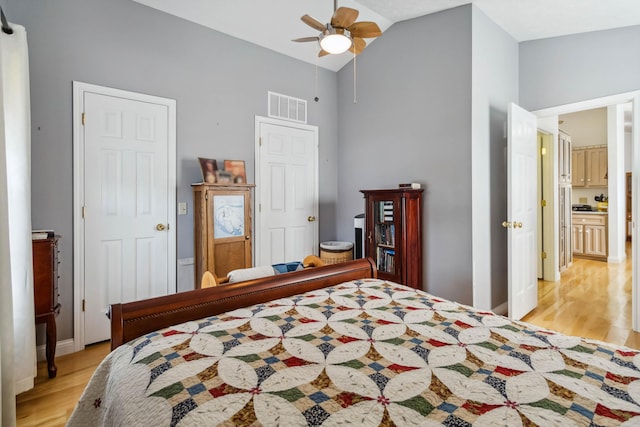 bedroom featuring light wood finished floors, ceiling fan, vaulted ceiling, and visible vents