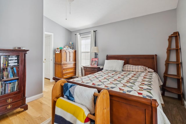 bedroom with baseboards, vaulted ceiling, and light wood-type flooring