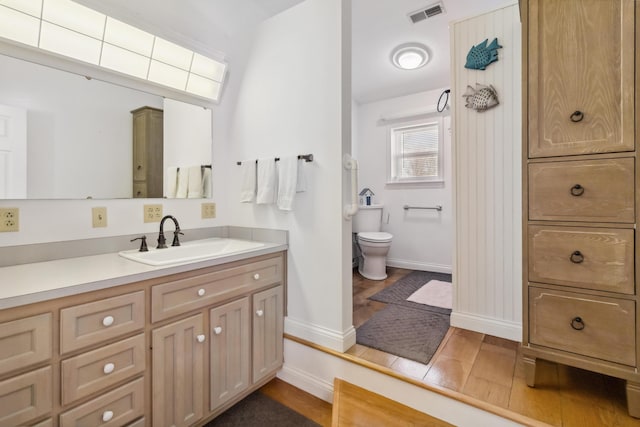 bathroom with visible vents, baseboards, toilet, wood finished floors, and vanity