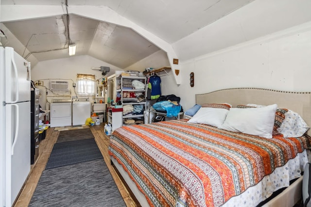 bedroom with a wall mounted AC, freestanding refrigerator, washing machine and clothes dryer, wood finished floors, and lofted ceiling