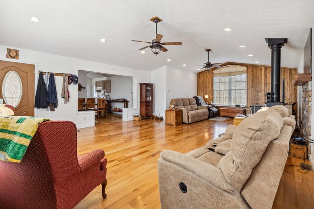 living area featuring vaulted ceiling, recessed lighting, a wood stove, ceiling fan, and light wood-style flooring