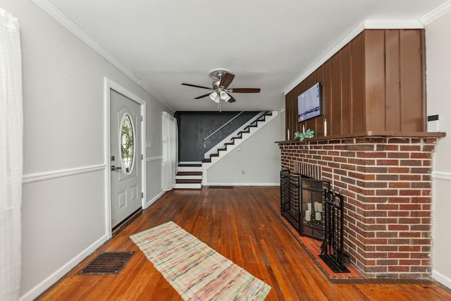 foyer featuring crown molding, visible vents, hardwood / wood-style flooring, and a fireplace