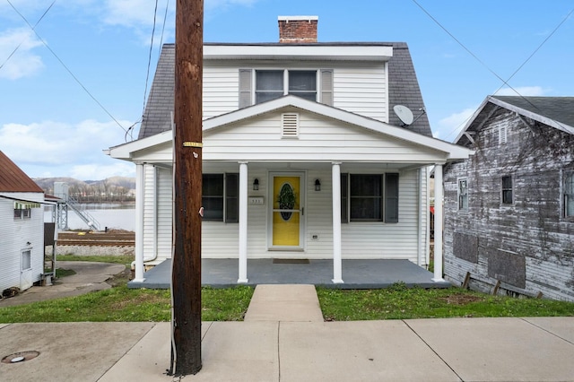 view of front of house featuring a chimney and a porch