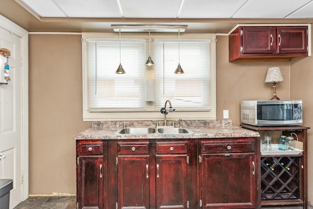 bar featuring stainless steel microwave, pendant lighting, and a sink