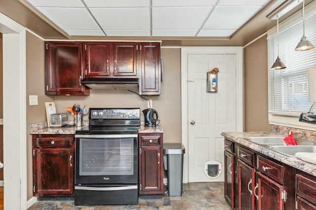 kitchen with reddish brown cabinets, a drop ceiling, under cabinet range hood, and black range with electric stovetop