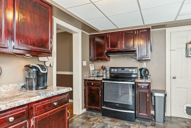 kitchen with baseboards, black / electric stove, under cabinet range hood, and reddish brown cabinets