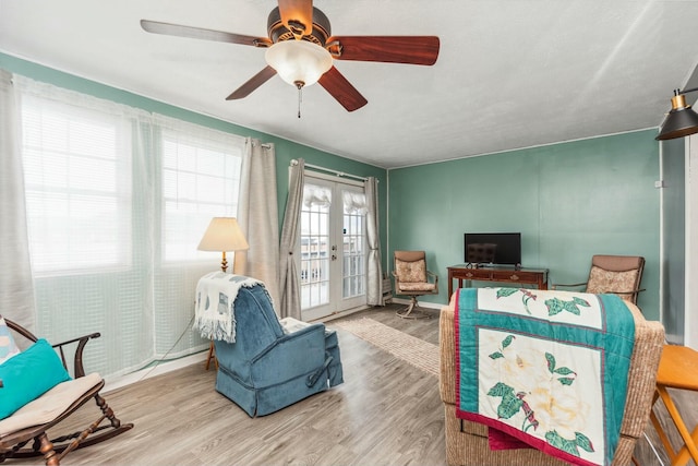 living area with baseboards, ceiling fan, french doors, and wood finished floors