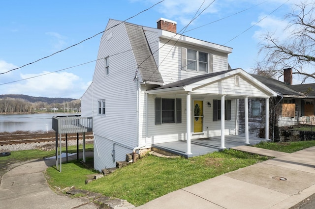 bungalow featuring a water view, covered porch, a chimney, and a front yard