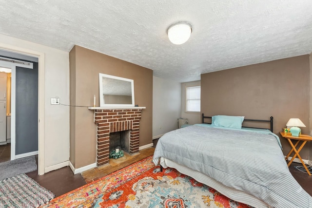 bedroom featuring baseboards, a textured ceiling, and a fireplace