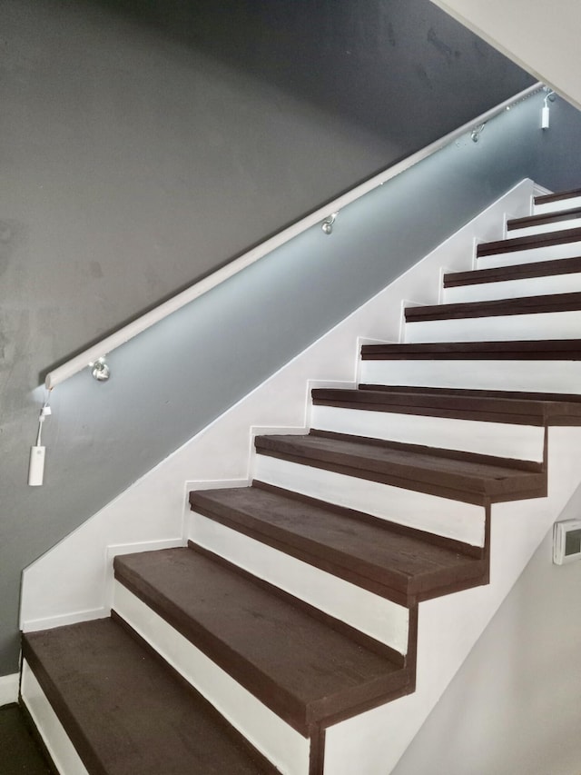 stairs featuring track lighting and baseboards